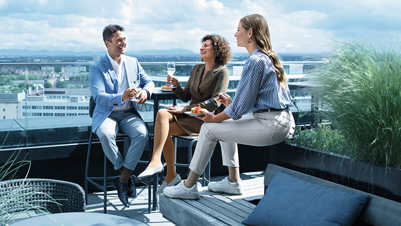 A man and two women wearing compression stockings are on a roof terrace