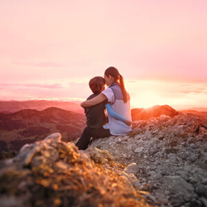 Une mère, son enfant dans les bras, est assise au sommet d'une montagne et contemple le coucher de soleil Une mère, son enfant dans les bras, est assise au sommet d'une montagne et contemple le coucher de soleil