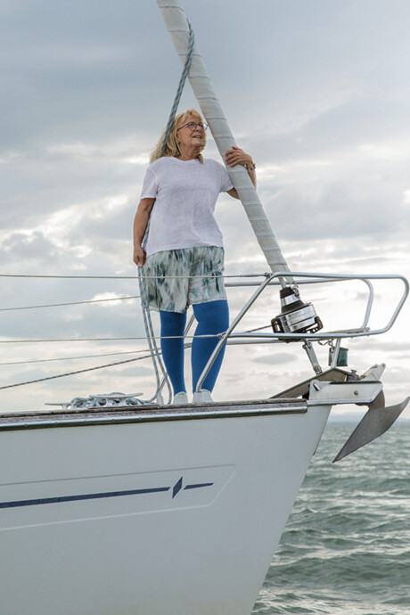 A woman with lymphoedema is standing on the deck of a boat. She is wearing blue compression stockings A woman with lymphoedema is standing on the deck of a boat. She is wearing blue compression stockings