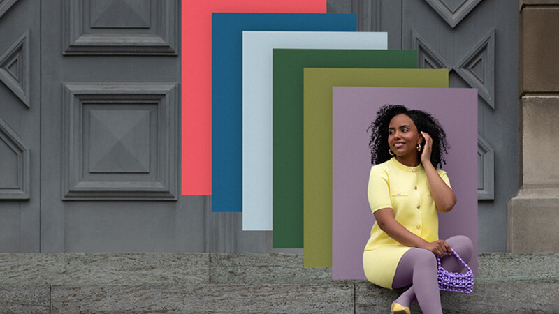 Una donna è seduta su una rampa di scale e indossa indumenti compressivi in tonalità coordinate; alle sue spalle sono disposte delle superfici cromatiche sovrapposte nei vari colori di tendenza.