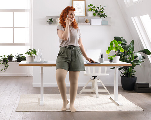 A woman is standing in her living room, talking on the phone