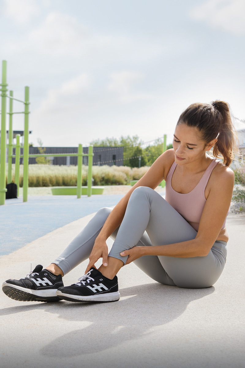 Woman is holding her ankle because of pain