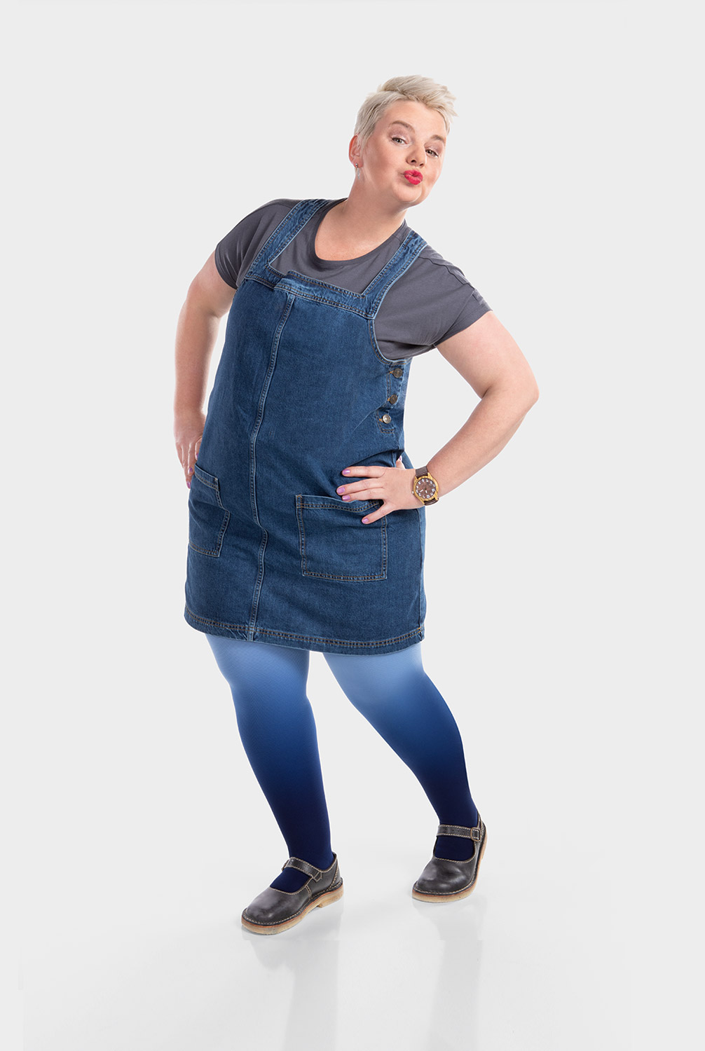 A woman is wearing a denim pinafore dress and compression hosiery in dip-dye blue A woman is wearing a denim pinafore dress and compression hosiery in dip-dye blue