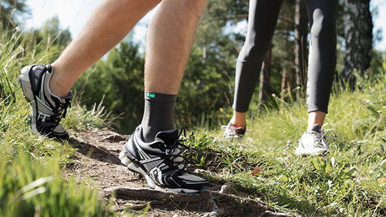Jemand läuft über einen Feldweg und trägt dabei eine Sprunggelenkbandage Jemand läuft über einen Feldweg und trägt dabei eine Sprunggelenkbandage